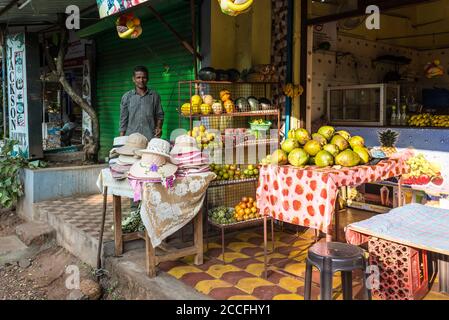 Candolim, North Goa, Inde - 23 novembre 2019 : un vendeur local vend des fruits frais et des chapeaux à Candolim, North Goa, Inde. Banque D'Images