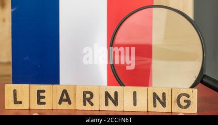 Concept d'apprentissage en français, drapeau et mot d'apprentissage écrit sur un bloc de bois Banque D'Images
