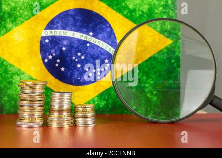 Loupe et pièces en face du drapeau du Brésil, concept d'économie de pays Banque D'Images