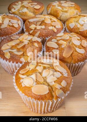 Muffins frais faits maison aux saveurs de banane dans des boîtes en papier, chacun recouvert d'une arrosette de noix d'amandes en flocons. Banque D'Images