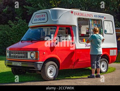 Gros plan d'une femme achetant de la crème glacée auprès d'un vendeur dans une vieille fourgonnette Bedford, sous le soleil d'été, au parc aquatique Rutland, Normanton, Angleterre, Royaume-Uni. Banque D'Images