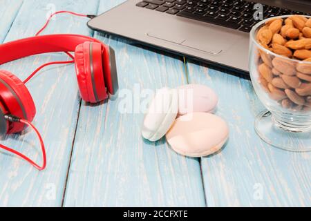 Ordinateur portable ouvert avec une tasse d'amandes, des guimauves et des écouteurs rouges. Banque D'Images