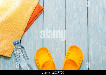 Bouteille d'eau et serviettes brillantes, schiste jaune sur fond bleu. Banque D'Images