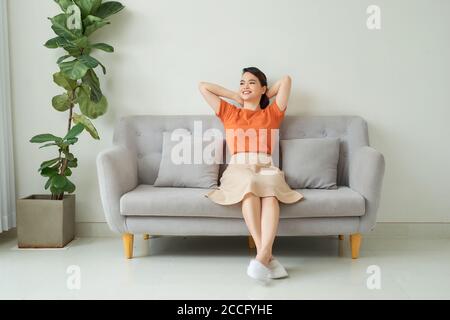 Vue sur toute la longueur avant paisible millénaire jolie femme se reposant sur un canapé confortable dans le salon. Banque D'Images