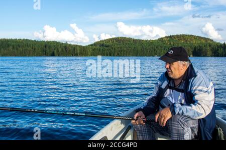 Vieil homme qui pêche au lac depuis un bateau , Finlande Banque D'Images