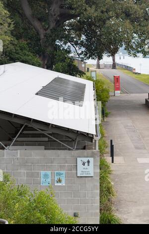 Une douche solaire et des toilettes sont situées près d'une falaise près de la zone de camping de l'île Cockatoo, dans le port de Sydney, en Australie Banque D'Images