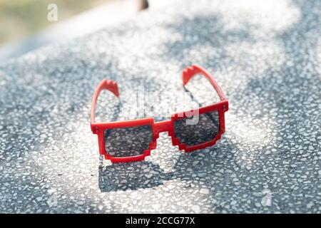 Lunettes de soleil rouges avec verres noirs en gros plan par temps ensoleillé. Mise au point sélective Banque D'Images