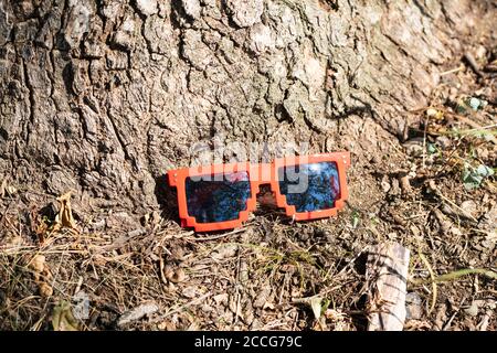 Lunettes de soleil rouges avec verres noirs en gros plan par temps ensoleillé. Mise au point sélective Banque D'Images