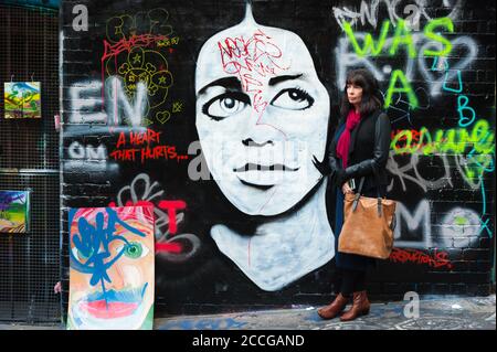 Les touristes féminins se trouvent à côté de l'art de la rue coloré le long de la voie ACDC à Melbourne, Victoria, Australie. Banque D'Images