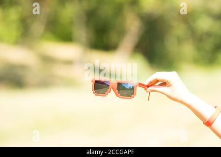 Lunettes de soleil rouges modèle pixel avec lentilles noires en gros plan dans une journée ensoleillée. Mise au point sélective Banque D'Images