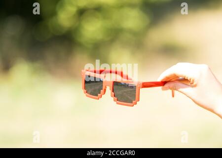 Lunettes de soleil rouges modèle pixel avec lentilles noires en gros plan dans une journée ensoleillée. Mise au point sélective Banque D'Images