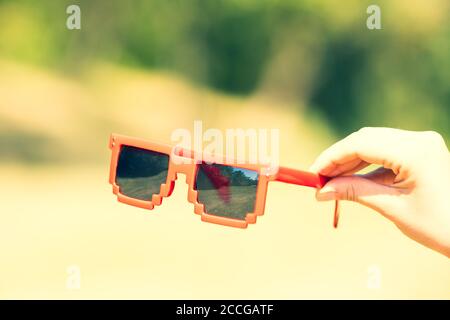 Lunettes de soleil rouges modèle pixel avec lentilles noires en gros plan dans une journée ensoleillée. Mise au point sélective Banque D'Images