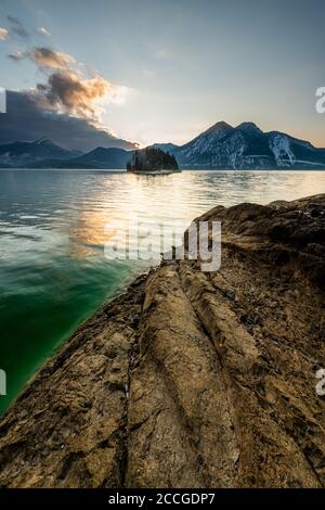 Ambiance nocturne avec du rock sur les rives du Walchensee, en arrière-plan l'île de Sassau et le Herzogstand avec un front de nuage foncé Banque D'Images