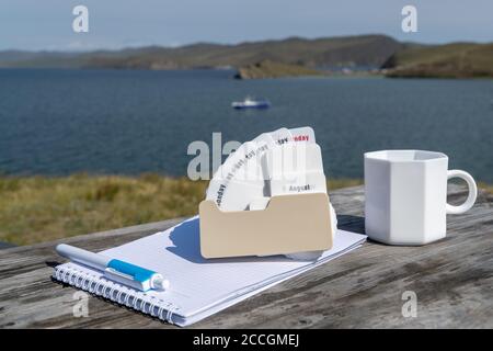 Calendrier, carnet et mug sur une table en bois sur le fond du lac. Mise au point sélective. Banque D'Images