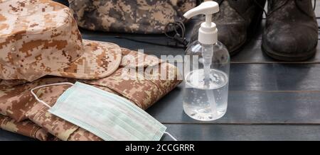 Concept de protection du coronavirus de l'armée. Désinfectant pour les mains, masque de protection médical et équipement militaire américain sur fond de bois bleu. L'épidémie de Covid 10 préve Banque D'Images