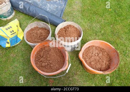 gros plan de 4 seaux de sable pour la construction de la maison extensions sur l'herbe à l'extérieur en été Banque D'Images