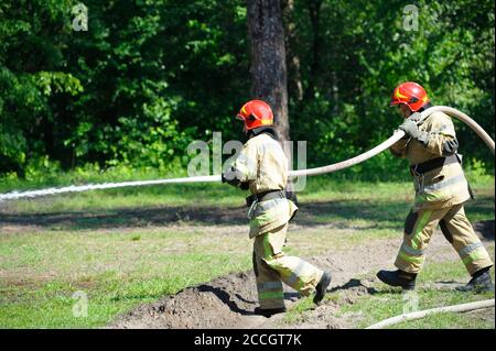 Équipe de lutte contre les incendies : pompiers dans les ensembles protecteurs arrosoir la forêt avec une seringue Banque D'Images