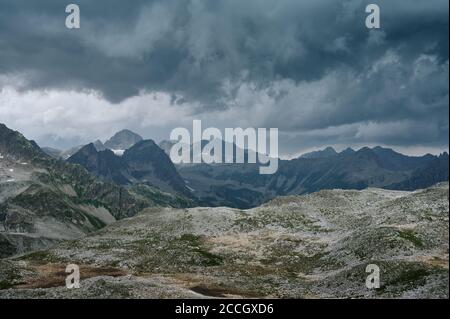 Paysage de montagne sombre avec ciel nuageux, chaînes rocheuses et pics avec glaciers et champs de neige. Vallée naturelle sauvage Banque D'Images