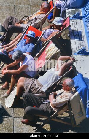 Un groupe de touristes âgés assis dans des chaises longues bénéficiant du soleil d'été. Hastings, East Sussex, Angleterre, Royaume-Uni Banque D'Images