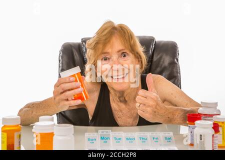 Une femme âgée donne des Thumbs sur les médicaments qu'elle utilise dans Boîte hebdomadaire Pill Banque D'Images
