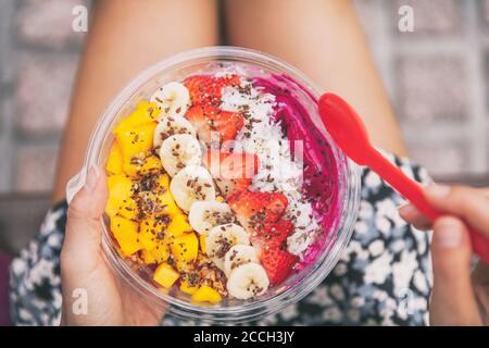 Fruits santé petit déjeuner pitaya bol. Fille mangeant des fruits smoothie assis à l'extérieur du parc pour la pause déjeuner. La nourriture végétalienne en gros plan. Purée de libellules Banque D'Images