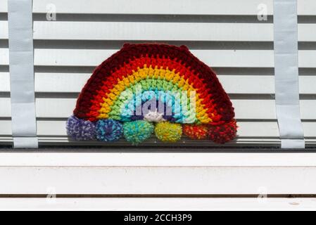 Tricoté arc-en-ciel dans la fenêtre d'accueil pour remercier le NHS et les travailleurs clés pendant la pandémie du coronavirus COVID-19. Fenêtre de propriété avec store blanc Banque D'Images