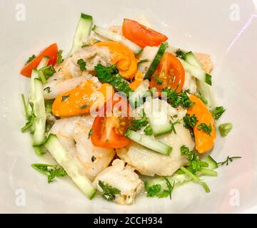 Délicieux repas de luxe composé de noix de Saint-Jacques et de crevettes sautées dans du beurre de persil à l'ail, réfrigéré et servi sur un lit d'avocat frais et de salade Banque D'Images