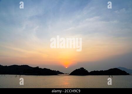 Observation du coucher du soleil à Yam O, sur l'île de Lantau, à Hong Kong. Avec un ciel clair et peu de nuages, le soleil peut être vu clairement. Banque D'Images