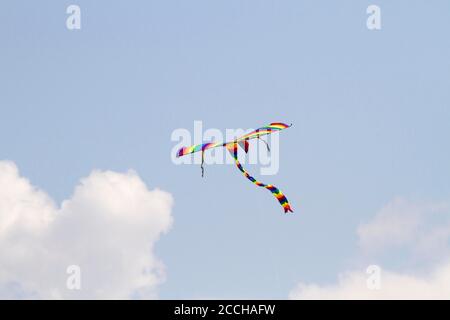 Cerf-volant préféré des enfants par temps venteux au printemps, ciel bleu et nuages blancs. Un cerf-volant coloré oscille dans le vent. Banque D'Images