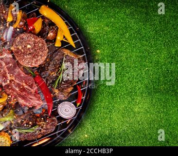 Vue de dessus de la viande fraîche et de légumes sur la grille placée sur l'herbe. Barbecue, grill et food concept Banque D'Images