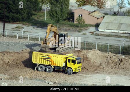 Excavation, camion et godet. Excavation de fondations d'une construction. Les tombereaux attendent que la pelle hydraulique remplisse le sol. Banque D'Images