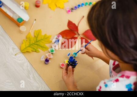 Petit enfant faire automne décoration de châtaignier, pommes de pin et glands Banque D'Images