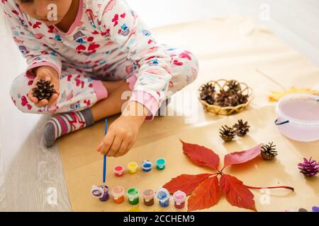 la petite fille peint la couleur sur les cônes de pin Banque D'Images