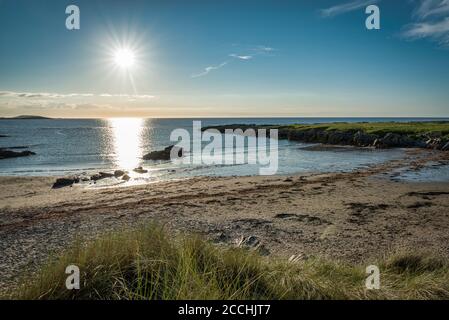 Dunes de sable couvertes d'herbe sur la plage de Ballyheirnan à Donegal en Irlande. Soleil se reflétant au large de l'océan Banque D'Images