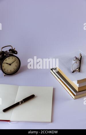 Encore plus de vie avec une vieille horloge sur le bureau avec des livres, un réveil, des lunettes et un fond blanc Banque D'Images