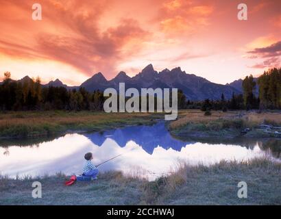 Garçon pêchant dans l'étang à Ox Bow Bend de Snake Rivière au-dessous de Grand Teton au coucher du soleil dans le Wyoming Banque D'Images