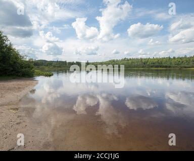 Ciel bleu avec des nuages blancs réfléchis dans l'eau fixe à un parc calme par jour d'été Banque D'Images