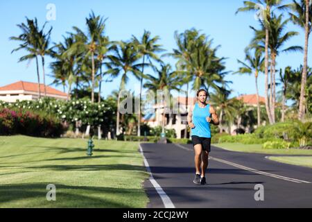 Running man sports fitness athlète coureur jogging sur la route résidentielle dans la ville tropicale. Entraînement d'été personne entraînement cardio en plein air Banque D'Images