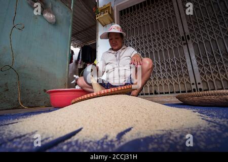 Hoi an / Vietnam - 18 janvier 2020: Femme vietnamienne qui s'écrase le riz à travers le tamis sur le sol Banque D'Images