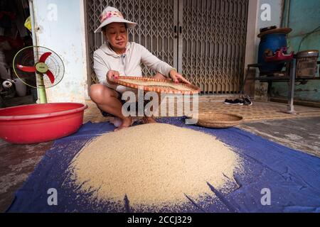 Hoi an / Vietnam - 18 janvier 2020: Femme vietnamienne qui s'écrase le riz à travers le tamis sur le sol Banque D'Images