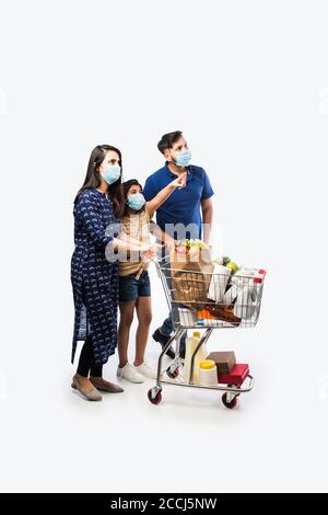 Famille indienne Shopping avec des enfants pendant l'épidémie de virus. Mère, père et fille portant un masque chirurgical achetant une épicerie dans un supermarché. Famille i Banque D'Images