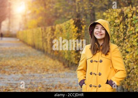 Adolescente vêtue d'un manteau à capuchon jaune dans le parc d'Augarten Vienne automne saison Banque D'Images