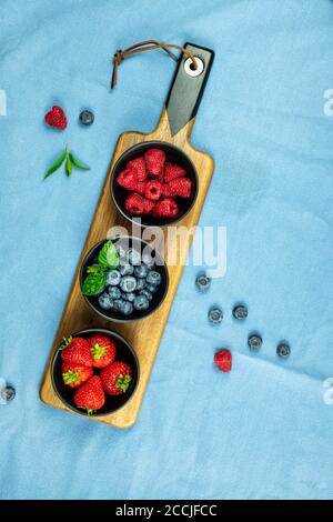 Sélection de fraises aux fruits bleuets et framboises sur un aliment plat et bol montrant des choix de nourriture saine Banque D'Images