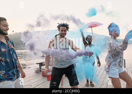Groupe d'amis debout sur un quai et dansant ils visite du festival des couleurs Banque D'Images