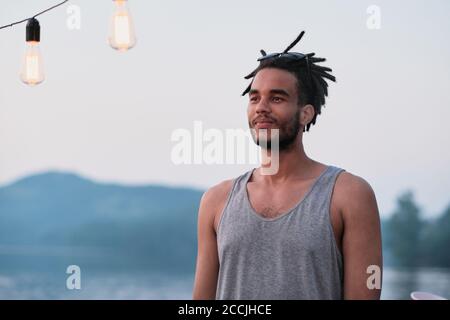 Jeune homme avec une coiffure élégante debout sur la nature et regarder la vue Banque D'Images