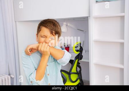 Portrait rapproché du petit garçon autiste mord les mains avec fort expression de face négative Banque D'Images