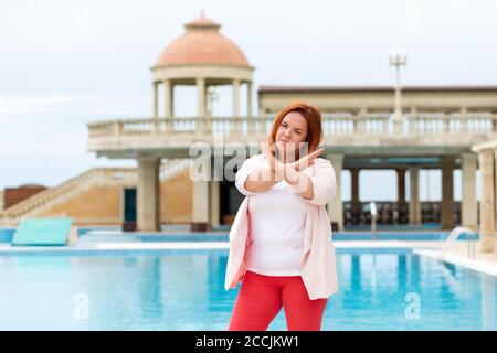 Émotions et expressions. Une femme caucasienne plus taille, qui montre un geste de prohibition avec ses mains. Extérieur. Banque D'Images