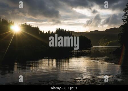 Coucher de soleil en Norvège sur un fjord, 'un cadre derrière la forêt à un fjord. Lumière du soir sur de beaux mountians en arrière-plan. Milieu de l'été à Scandin Banque D'Images