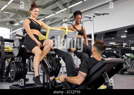 fit filles soutien sportif whie il fait des exercices sur l'équipement. homme pump jambes, dans la salle de gym moderne Banque D'Images