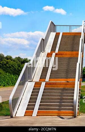 Les escaliers de la passerelle mènent au-dessus de l'autoroute avec ciel bleu et nuages blancs, concept de carrière, image verticale, espace de copie. Banque D'Images